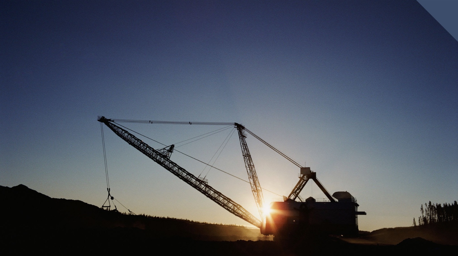 Silhouette of a mining dragline excavator against a dusk sky