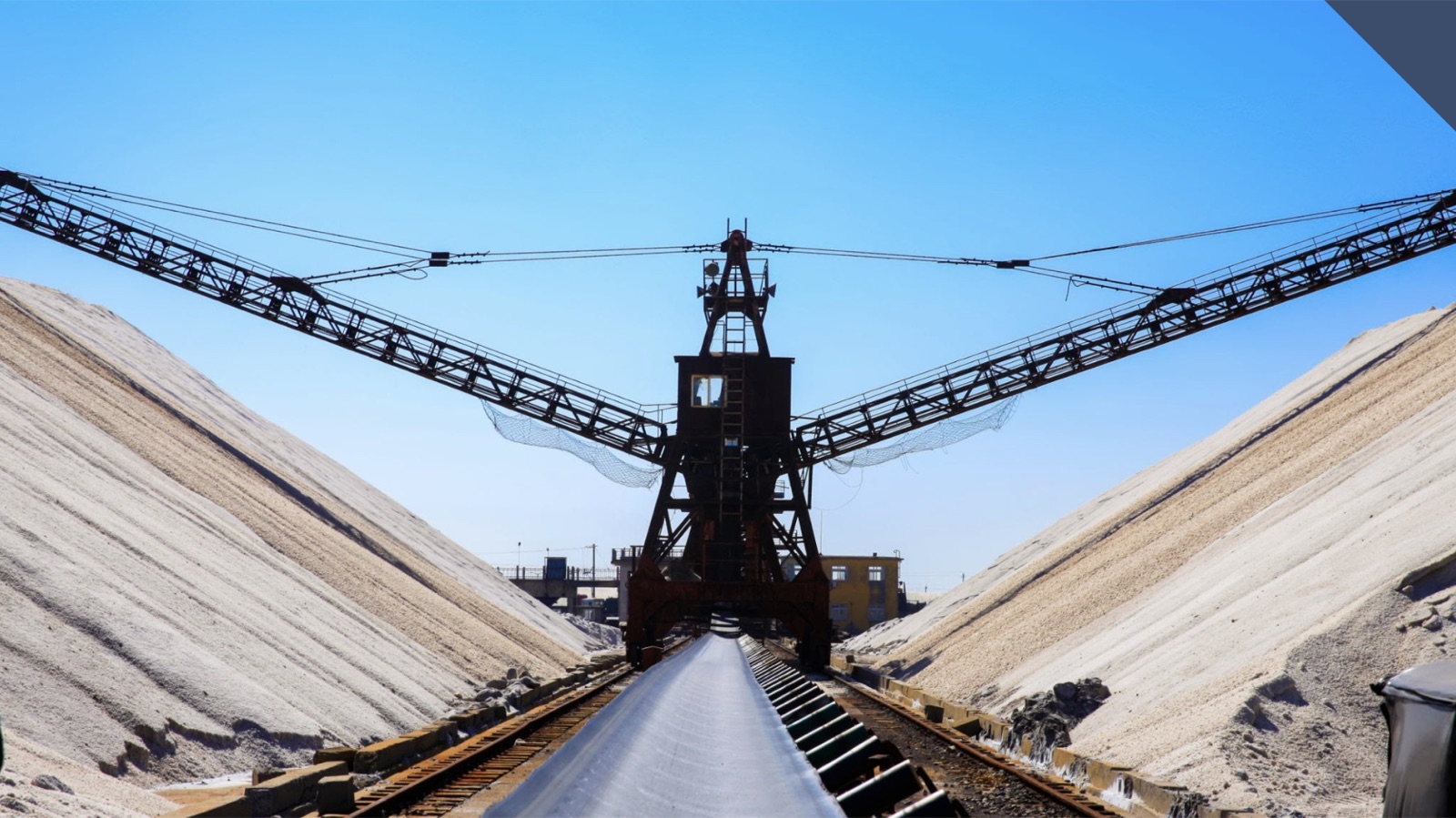 Elevated conveyor structure between stockpiles at a minerals processing site
